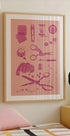 een ingelijste poster met naai- en knutselgereedschappen, waaronder scharen, spelden, naalden en andere naaigerelateerde artikelen, die aan de muur boven een bed hangt.