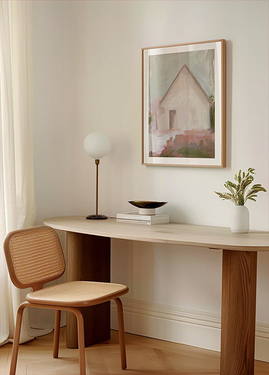 een moderne, minimalistische werkruimte met een houten bureau, een geweven stoel, een lamp en een ingelijst schilderij van een huis.