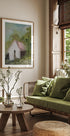 een gezellige woonkamer met een groot raam, een groene bank, een houten salontafel en een ingelijst schilderij van een huis.
